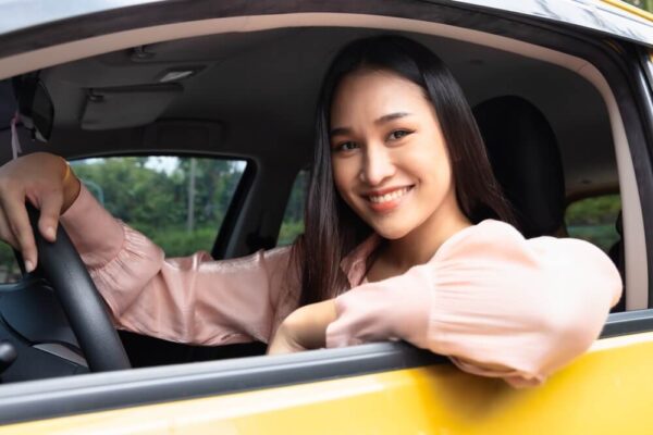 A photo of a woman sitting in her car smiling